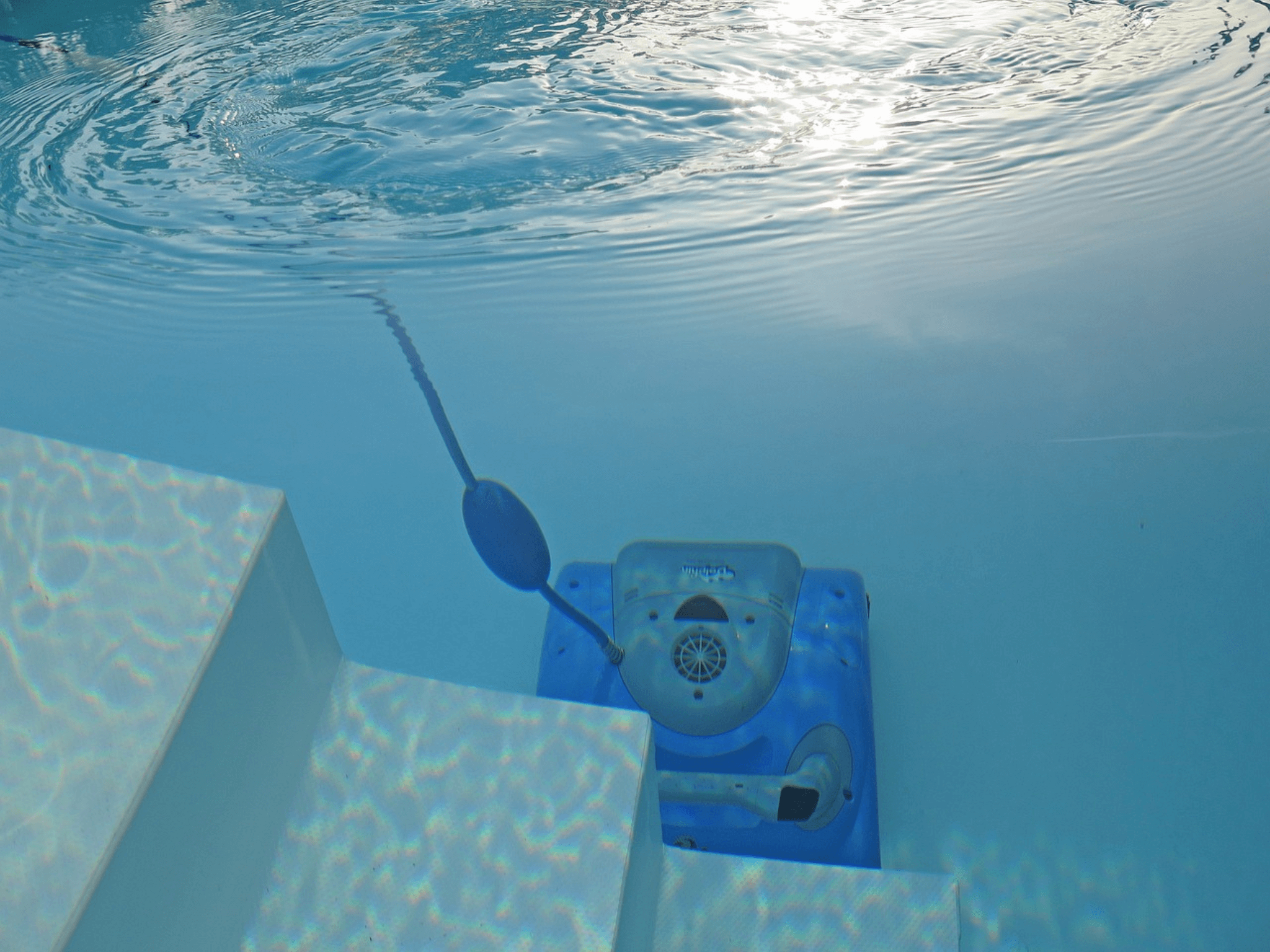 Piscina con un limpiafondos funcionando.