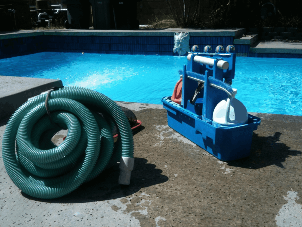 Productos y herramientas para la limpieza de la piscina en el borde.